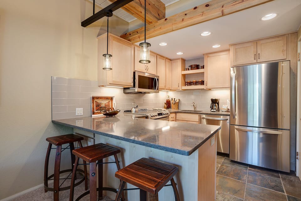 Your spacious kitchen invites culinary adventures with granite counters, stainless appliances, and rustic charm under exposed beams.