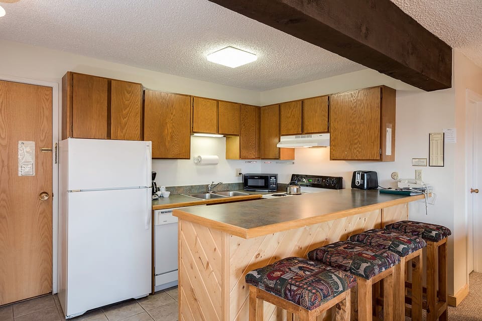 Your fully equipped kitchen features warm wood cabinetry, spacious countertops, and a breakfast bar perfect for morning coffee or casual meals.