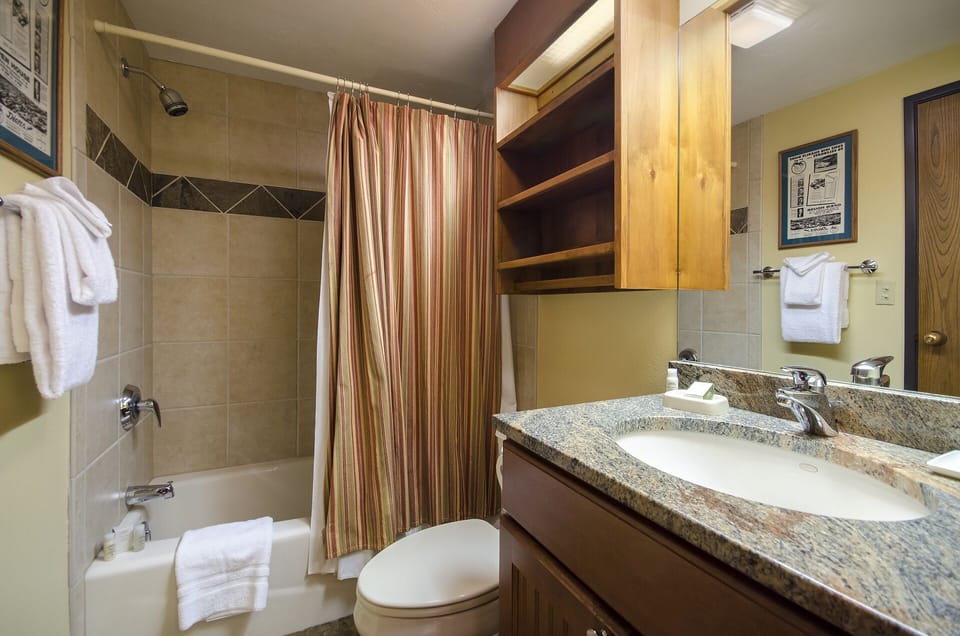 Your private bathroom features a granite vanity, plush towels, and a tiled tub-shower combo—everything you need to refresh and relax in comfort.