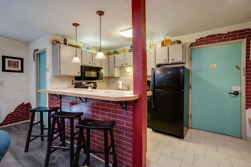 Your fully equipped kitchen features charming exposed brick, pendant lighting, and a breakfast bar where you can enjoy morning coffee.