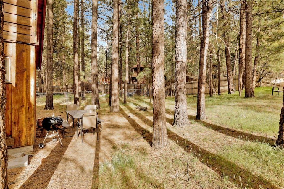 Comfortable outdoor chairs and a table to enjoy a delicious meal with peaceful views of the surrounding pine trees, creating the perfect spot to relax and enjoy the fresh mountain air.