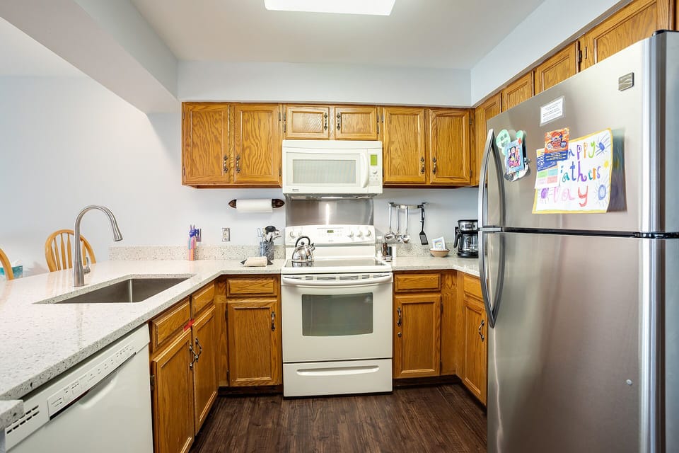 Your fully equipped kitchen awaits with stainless steel appliances, granite countertops, and warm wood cabinets—perfect for preparing meals together during your stay.