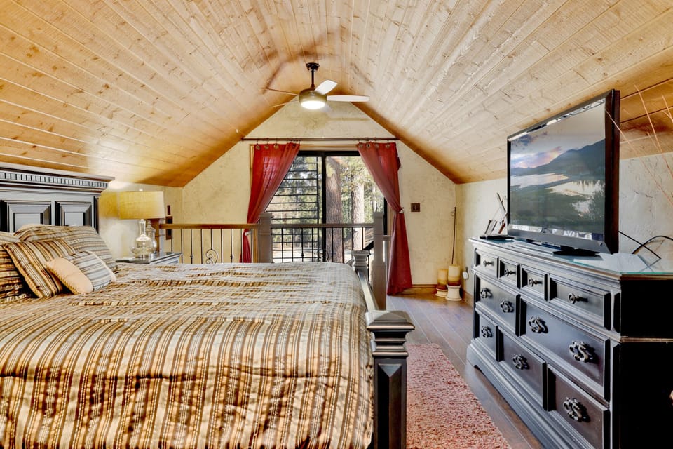 Another view of the primary suite showing the king-size bed and private balcony access overlooking the scenic wooded landscape.