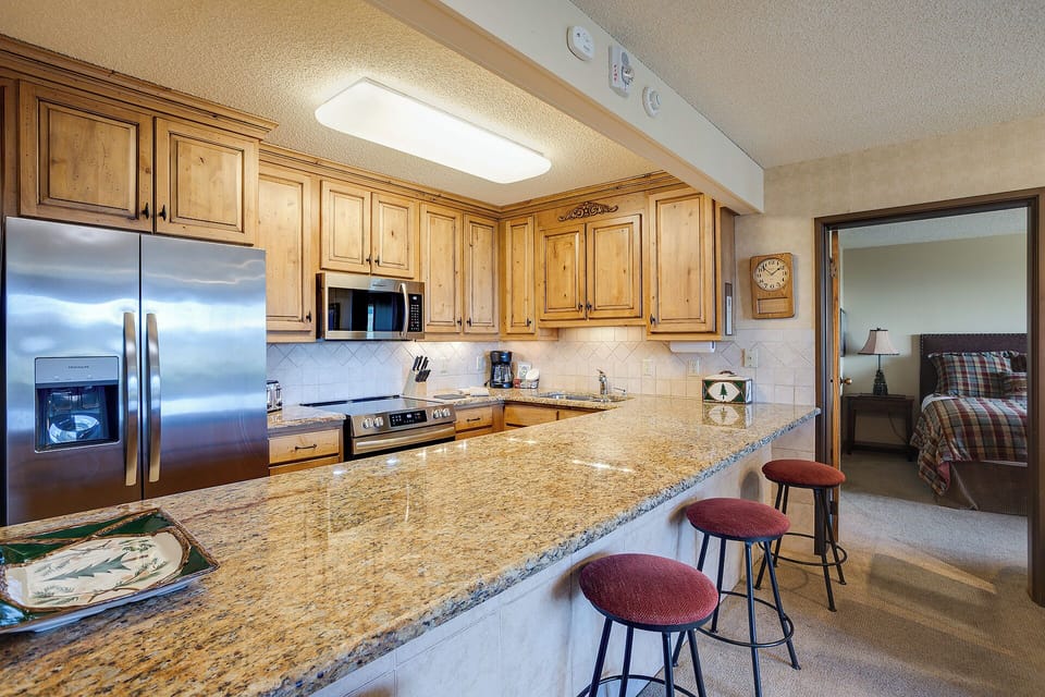 Your fully equipped kitchen features granite counters, stainless appliances, and cozy bar seating perfect for morning coffee or casual meals.