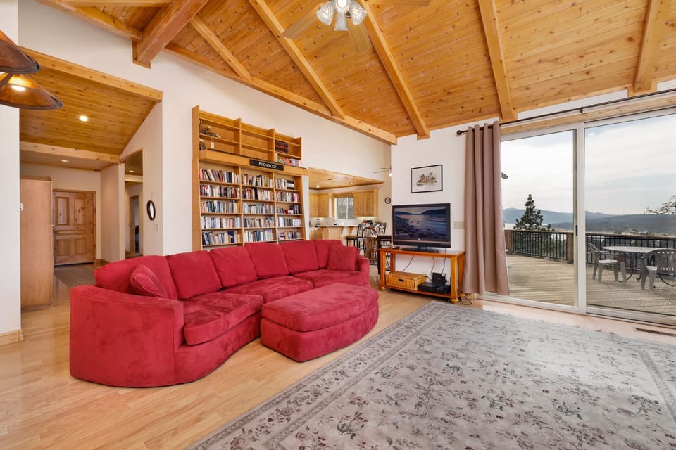 Cozy mountain living room with wood ceilings, stone fireplace, comfy seating, and smart TV—perfect for relaxing evenings, movie nights, and warm cabin vibes after outdoor adventures.