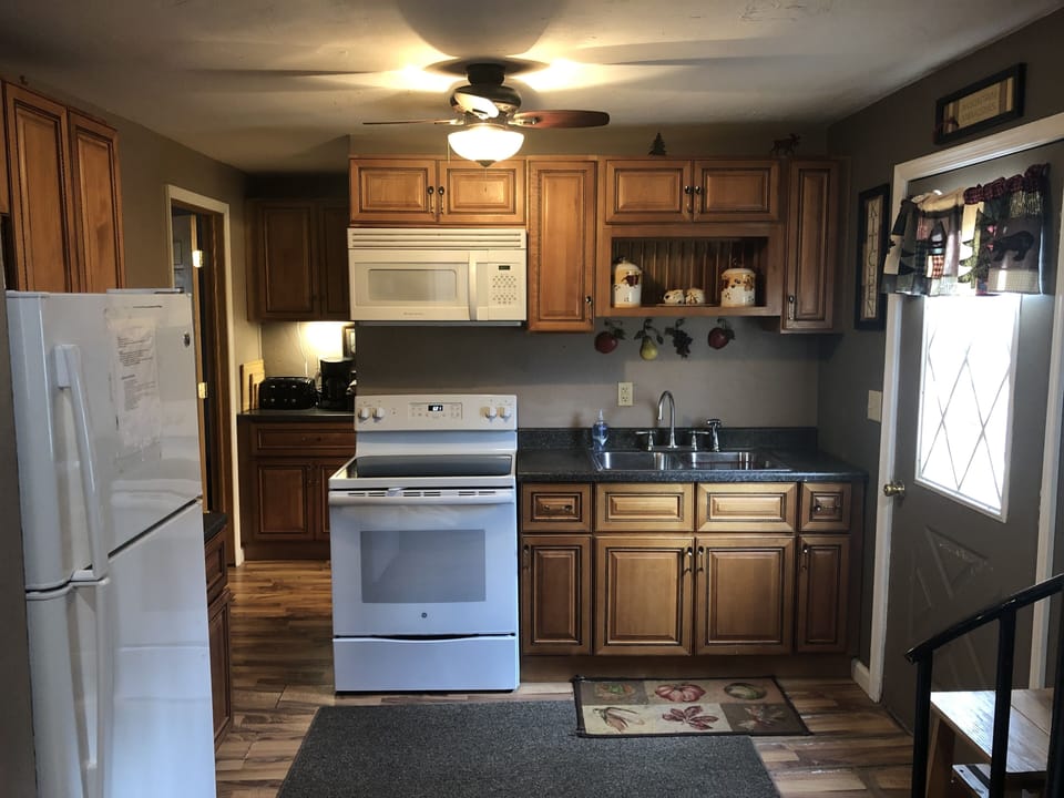 Kitchen with refrigerator, electric stove top, oven, and microwave. Ceiling fan.