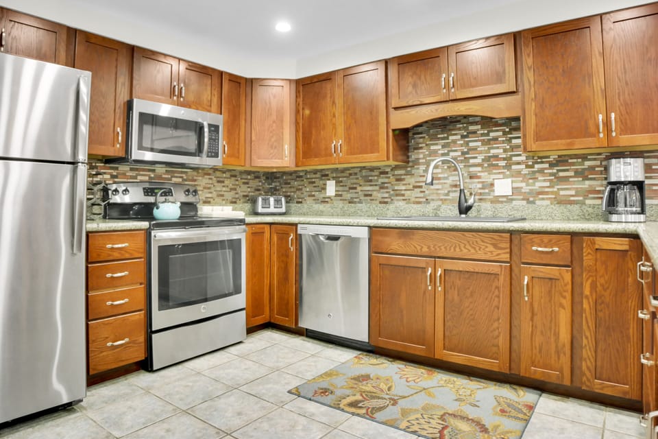 Park Station 113's kitchen has stainless steel appliances, wood cabinets, tile floors and interesting tile backsplash.
