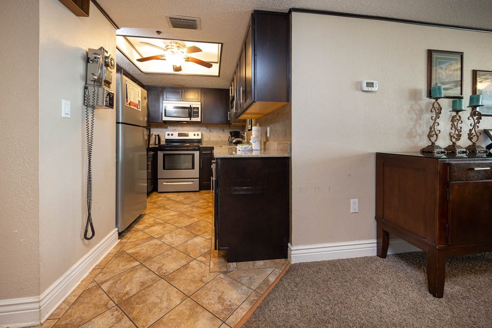 This kitchen features stainless appliances, granite countertops, and a charming vintage wall telephone
