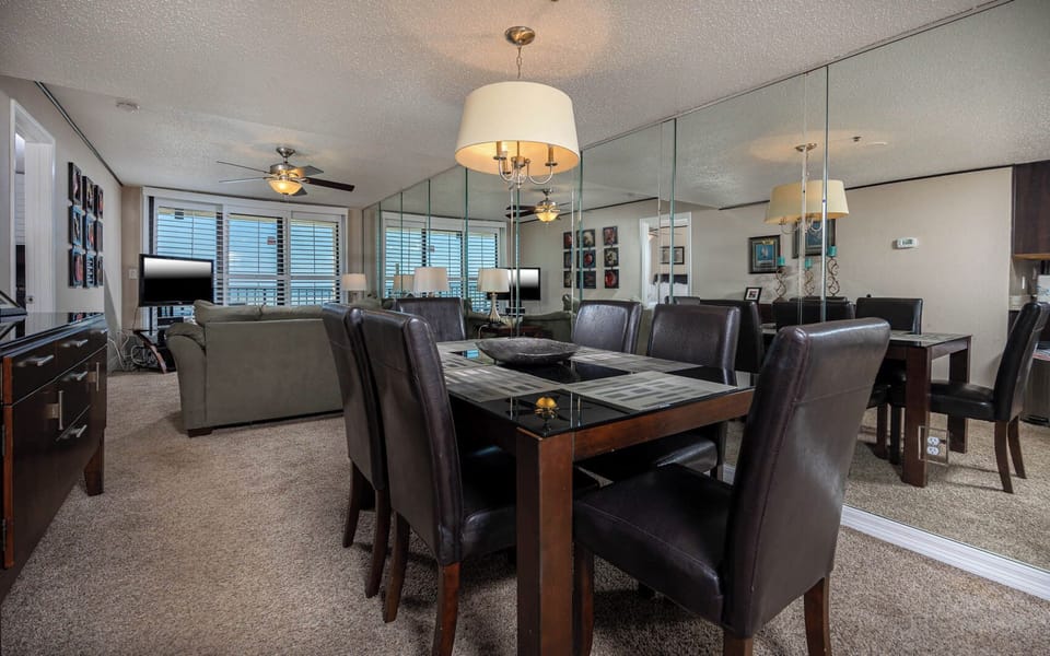 This inviting dining area features a sleek table, stylish chairs, and a cozy living space with a TV and beautiful views