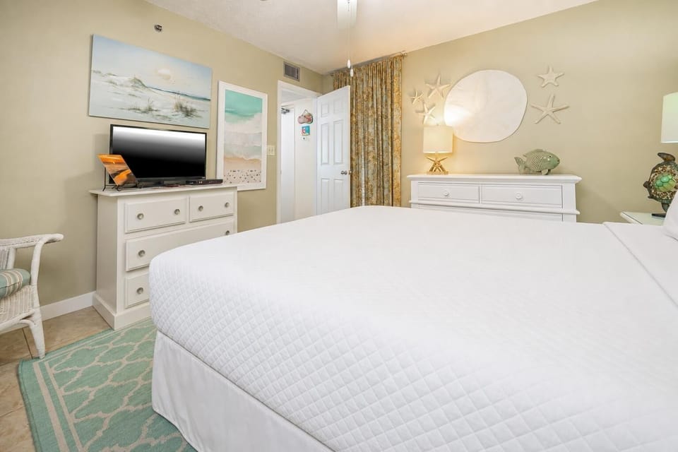 This cozy bedroom features soft beach-themed decor, a TV, and a welcoming atmosphere perfect for relaxation