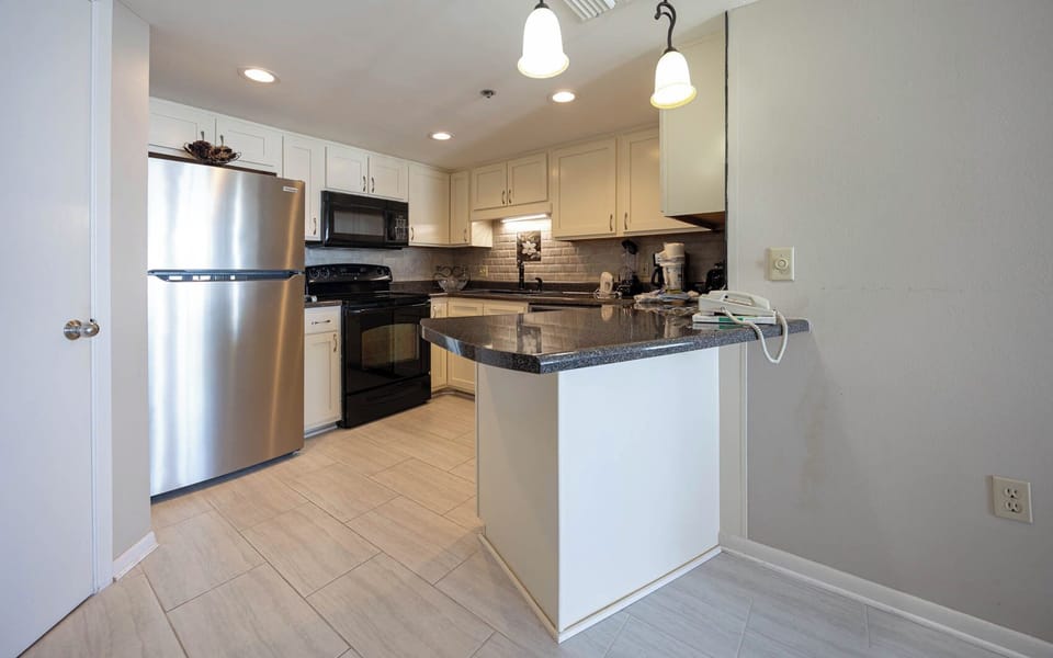 Prepare meals in this inviting kitchen featuring sleek appliances, ample counter space, and warm lighting
