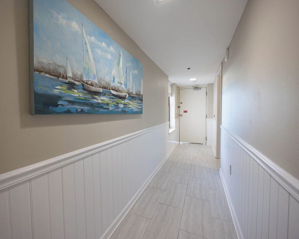 Walk down this inviting hallway adorned with coastal artwork, leading you to your relaxing retreat