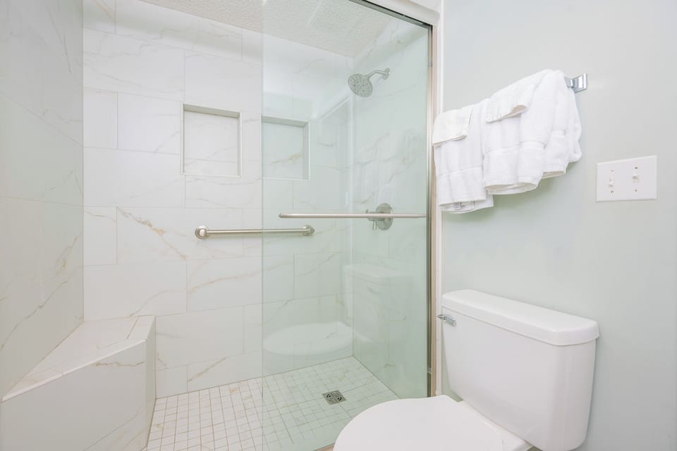 Bright tiles and a glass door create a fresh master bath space where you refresh after a day outside
