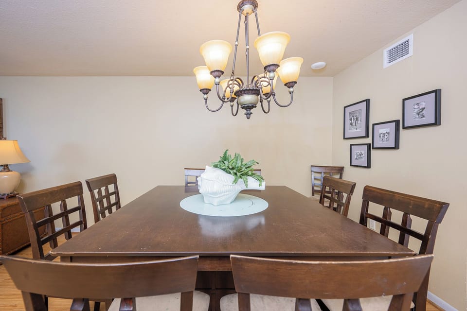 A wooden dining table with a shell centerpiece and framed photos, creating a welcoming atmosphere
