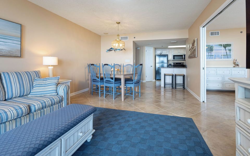 Living area features a striped sofa with queen sleeper, decorative accents, and a dining table with blue chairs