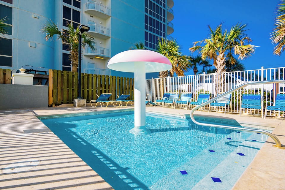 Splash with the kids under the playful mushroom fountain, surrounded by palm trees and lounge chairs