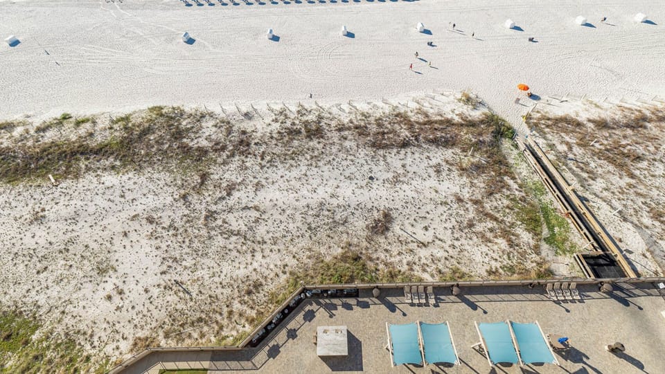 Relax on the balcony, enjoying the spacious pool area with lounge chairs and easy access to the beach just steps away