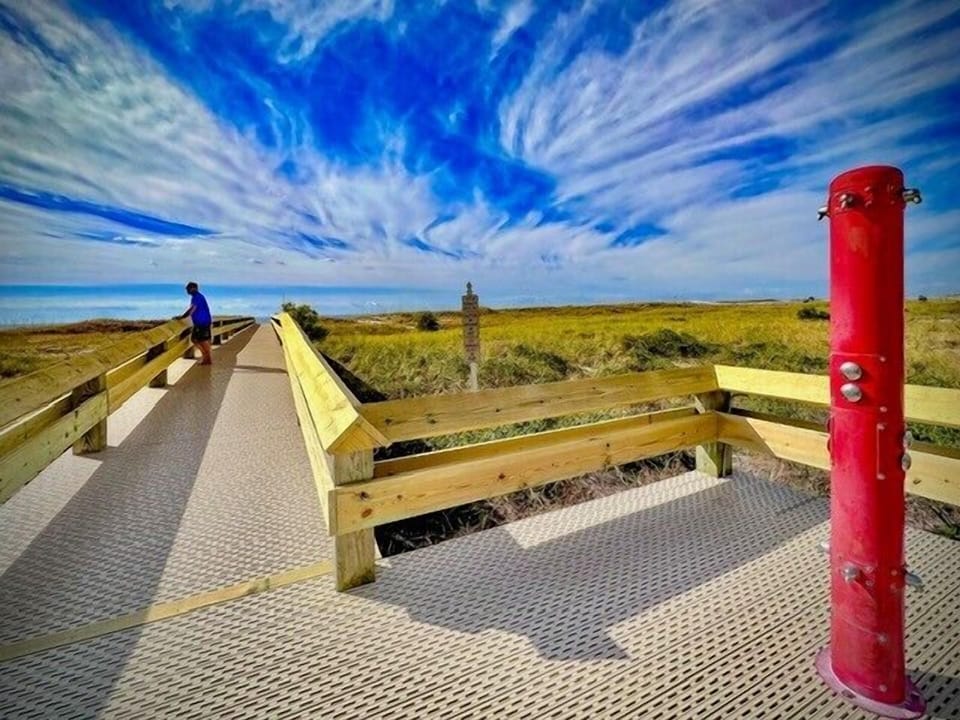 Stroll along the boardwalk with scenic views of lush greenery leading to the beautiful beachfront just ahead