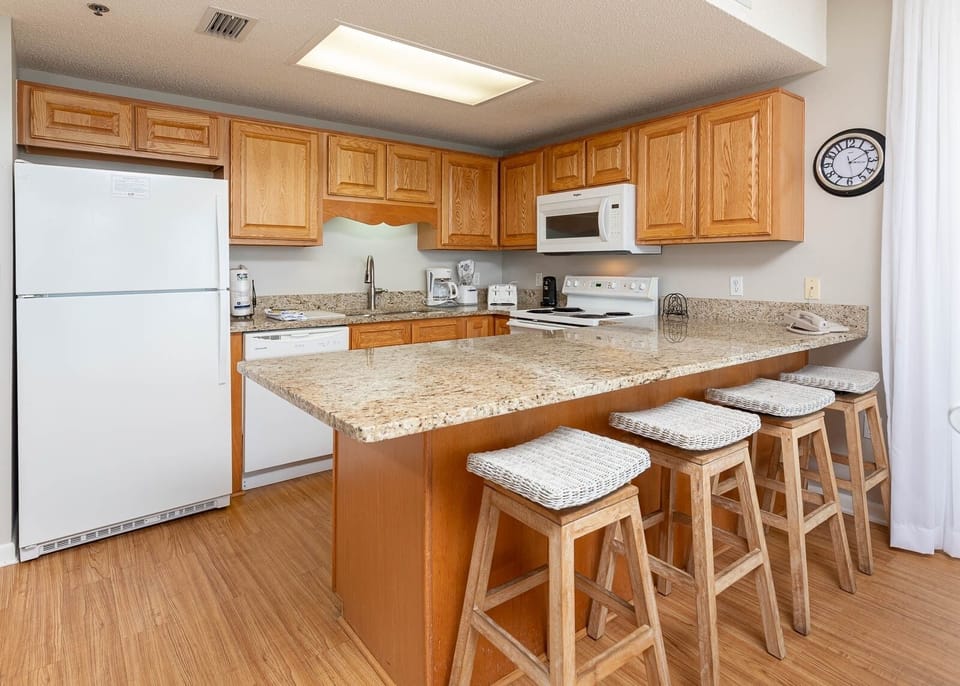 Warm wood cabinetry complements the spacious breakfast bar with woven stools, creating a welcoming atmosphere in the kitchen