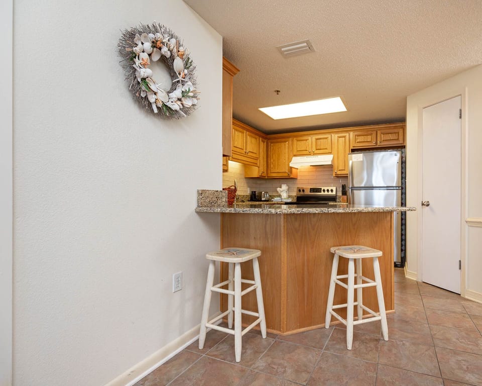 Kitchen area featuring stainless appliances, warm wood cabinetry, and a decorative coastal accents