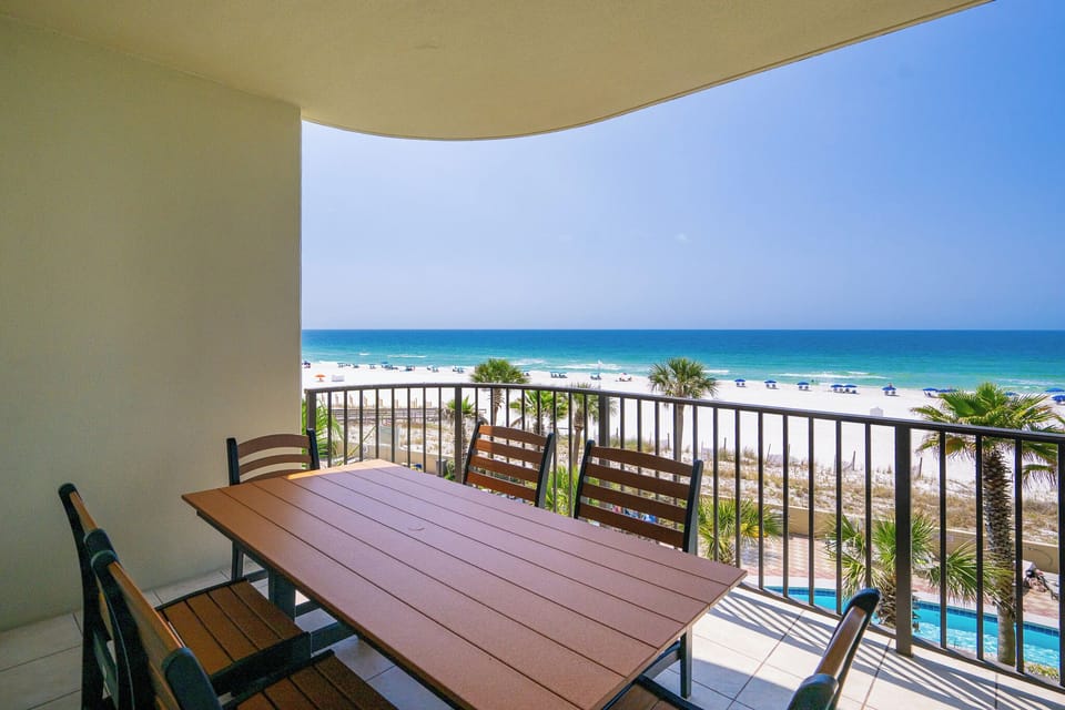 Your balcony dining area overlooks the beach and pool where you watch families enjoy the sun and water