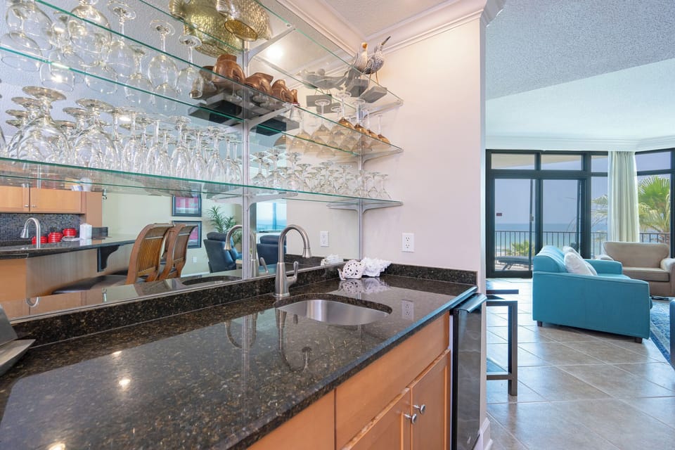 Glasses sparkle above the wet bar where you mix cool drinks and watch the sunlight dance through the living room windows