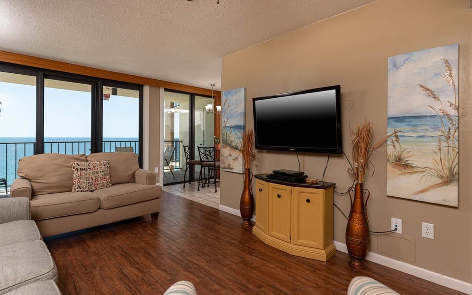 This cozy living area features a large TV, comfortable seating, queen sofa-sleeper, and a beautiful view from the balcony