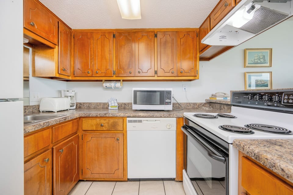 Kitchen featuring wooden cabinets, granite countertops, and modern appliances for a delightful cooking experience