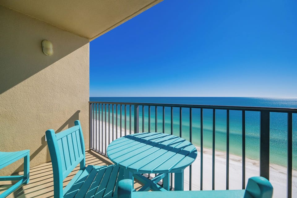 Enjoy a refreshing drink at the turquoise table set on the balcony, overlooking the serene water and shoreline
