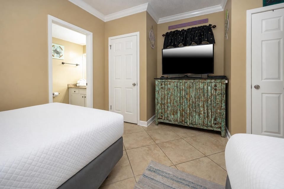Relax in a cozy guest bedroom featuring two double beds, a flat-screen TV, and charming decor for a restful stay