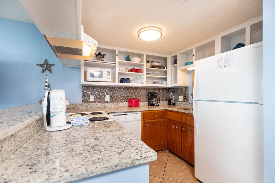 This kitchen features white appliances, granite countertops, and a vibrant coastal decor for a delightful cooking experience