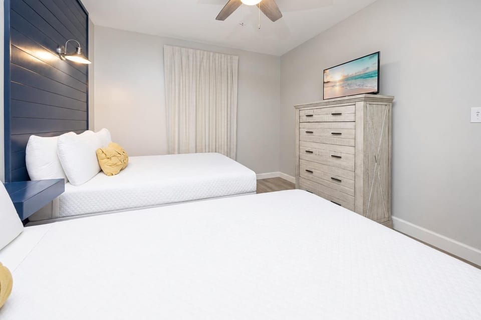Inviting guest bedroom featuring two comfortable double beds, a stylish dresser, TV, and soft lighting