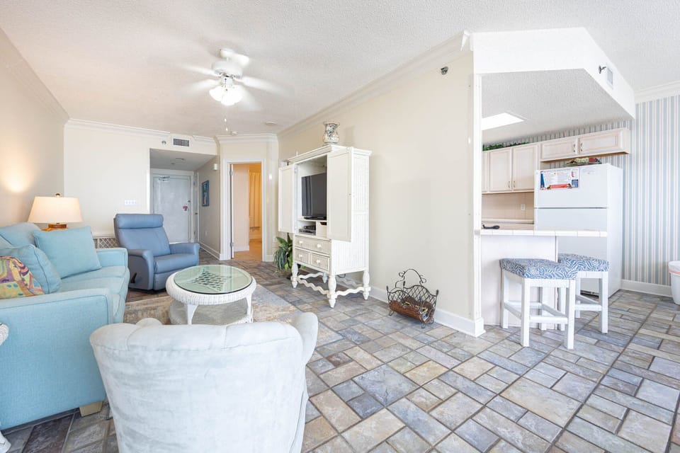 Cozy living area features a light blue sofa, plush chairs, stylish tile flooring, creating a relaxing vibe