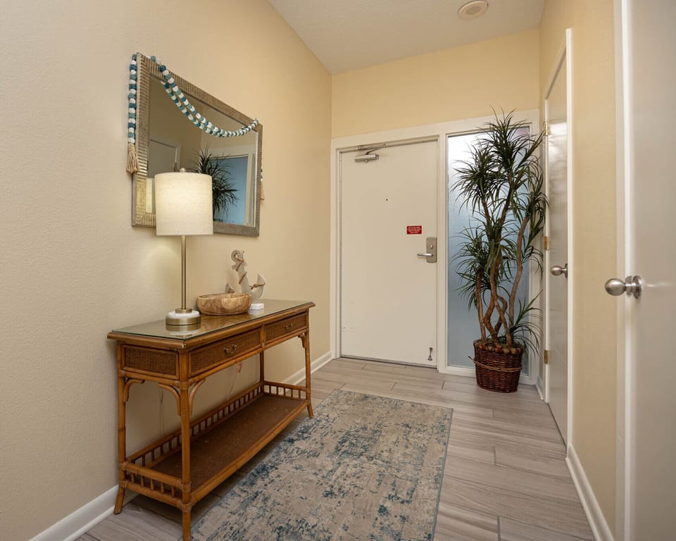 Step into a welcoming entryway featuring a stylish console table, decorative lamp, and a touch of greenery for warmth