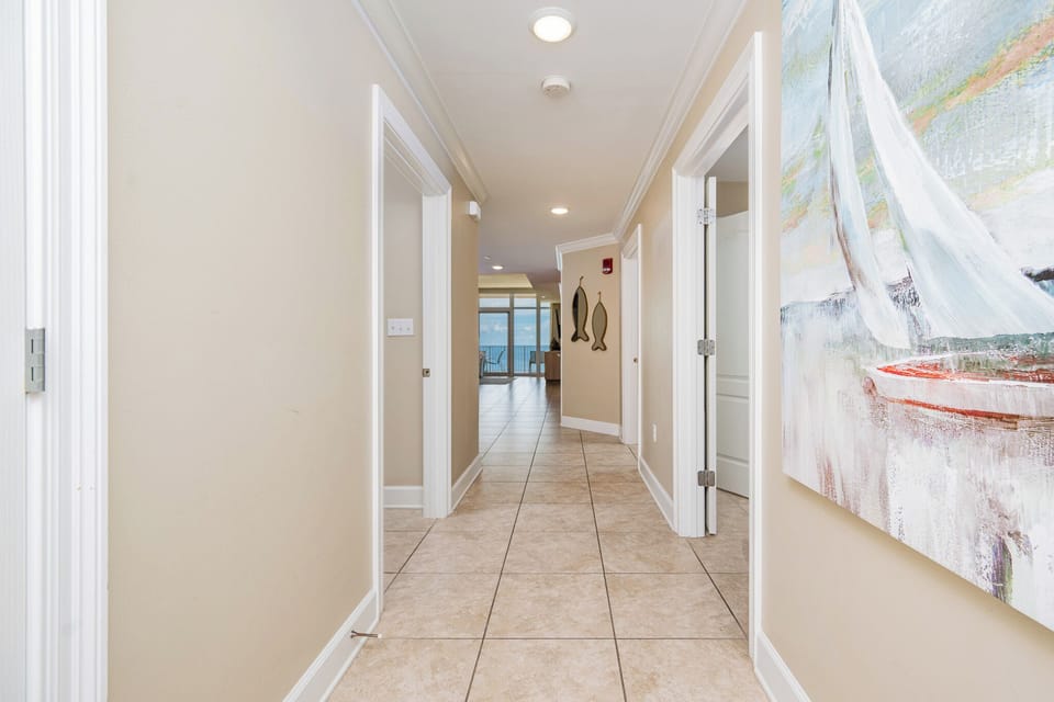 Step into a welcoming hallway adorned with coastal artwork and natural light, leading to stunning views of the beach