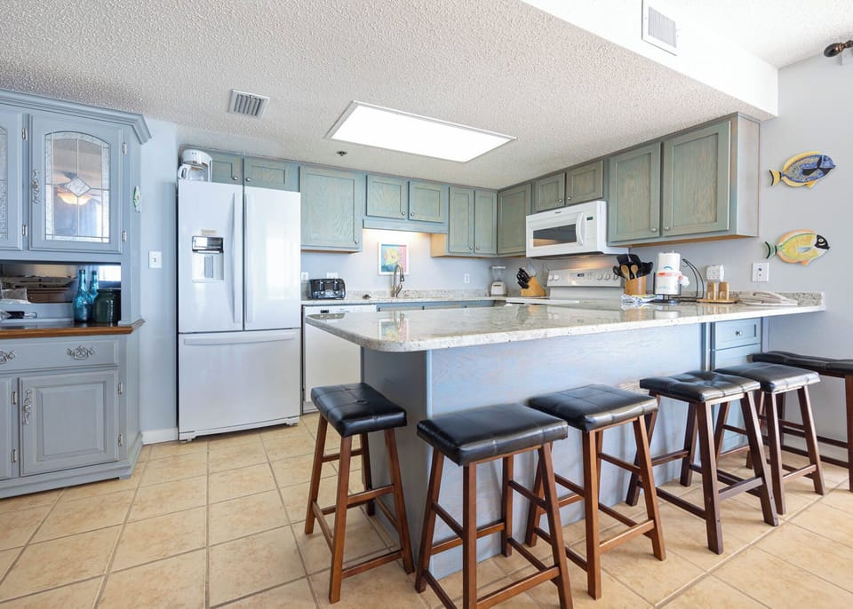 Bright kitchen features light blue cabinetry, a spacious breakfast bar with seating, and a well-equipped breakfast bar area