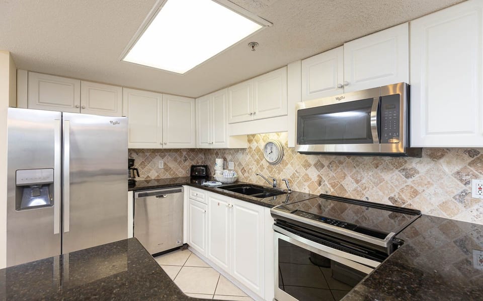 Modern kitchen featuring sleek cabinetry, modern appliances, a dark granite countertop, and a breakfast bar
