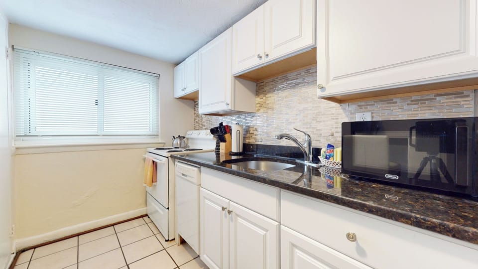 Well-lit kitchen with white cabinetry and modern appliances.