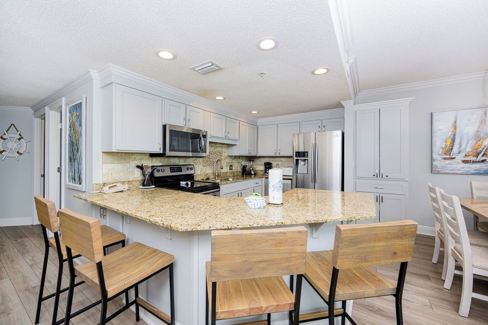 Gather around the granite countertop with seating, perfect for casual meals and conversation in this inviting kitchen
