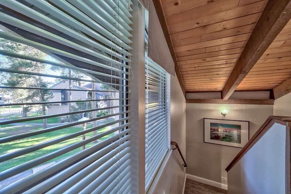 Sunlit staircase with rustic wood beams and peaceful outdoor views—simple, bright, and welcoming.

