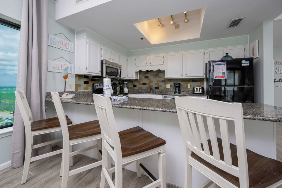 This kitchen features granite countertops, stainless appliances, and a cozy bar area with seating, perfect for casual dining