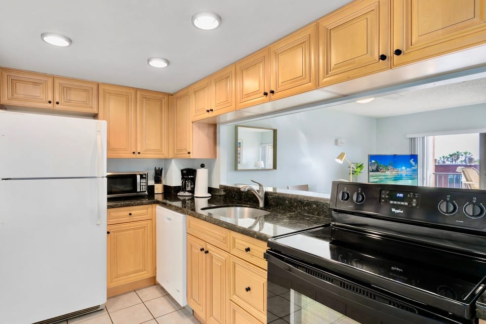 Fully equipped kitchen with warm wood cabinets and sleek black countertops