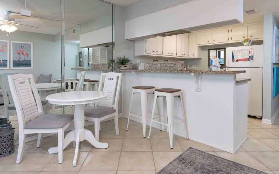 Inviting space featuring a breakfast bar and stools, white dining set, and stylish decor with playful flamingo art