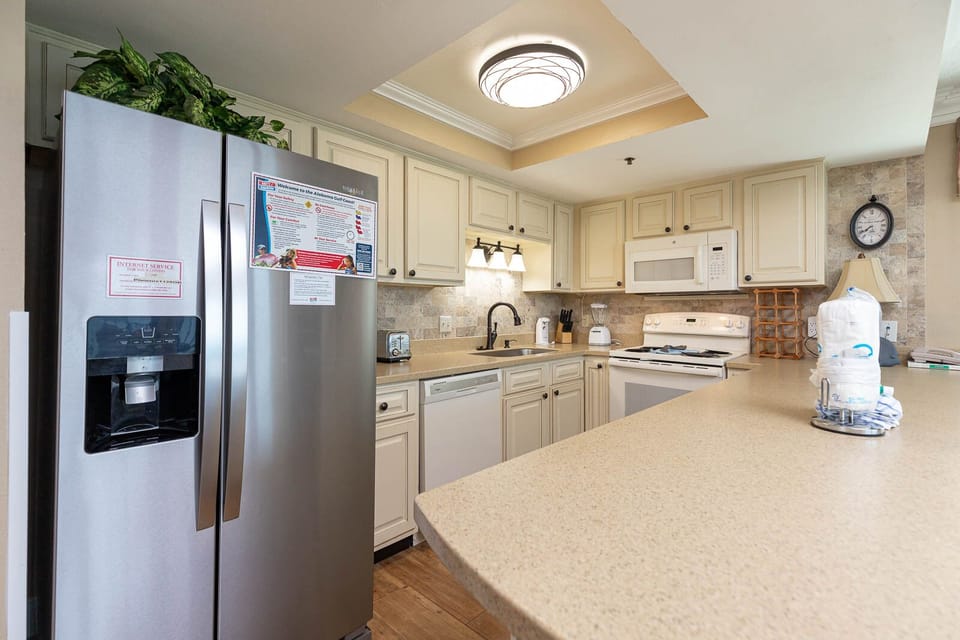 This kitchen features stainless and white appliances, granite countertops, and a convenient layout for meal preparation