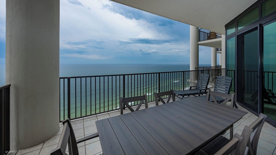 This spacious balcony features a large dining table and comfortable seating, perfect for enjoying beachfront views