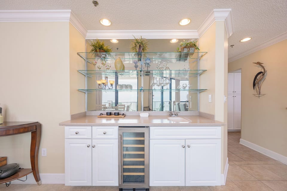 Enjoy a drink at the stylish wet bar area with elegant glassware and a wine cooler, perfect for preparing drinks with friends