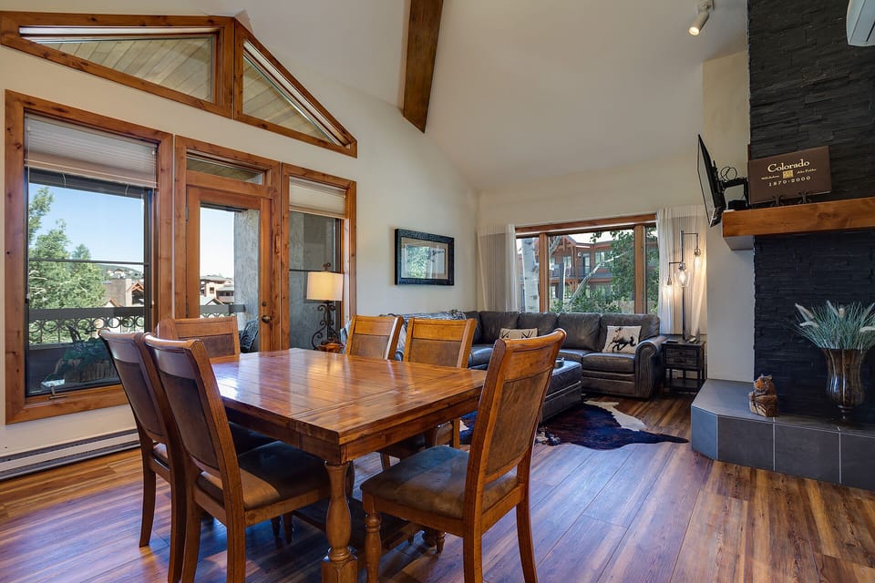 Gather around this warm dining table while natural light pours through beautiful wood-framed windows, creating perfect moments in your mountain retreat.