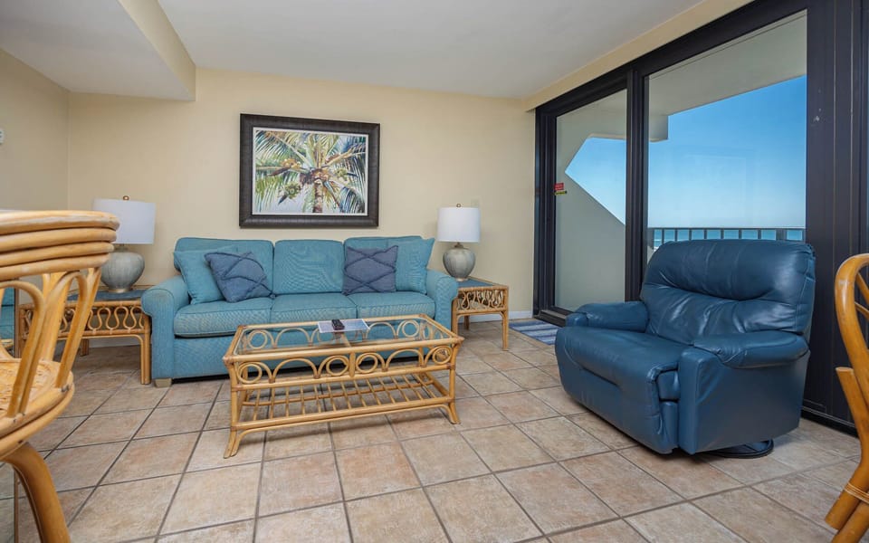 This inviting living room features a comfortable couch and a stunning beachfront view through large glass doors