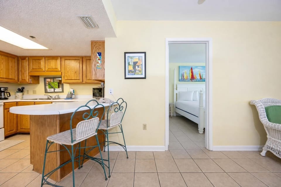 Kitchen area featuring wooden cabinetry, a breakfast bar with seating, and a view into a cozy bedroom with nautical decor