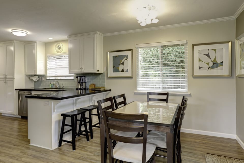 Charmingly designed dining area, comfortably accommodating six guests around the table, complemented by stylish bar stools at the kitchen counter for additional seating options.